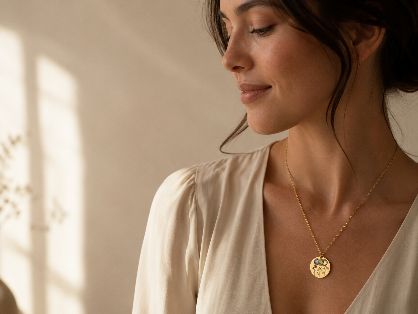 Woman wearing a gold birth flower and birthstone pendant necklace by Remember Me Jewelry